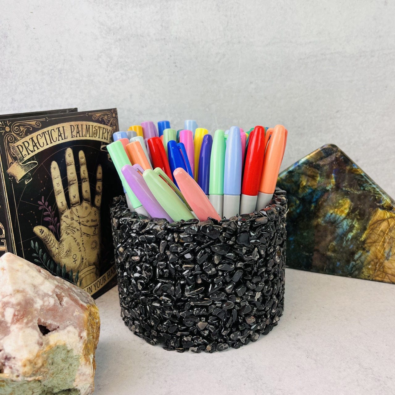 a black tourmaline stone holder , with assorted pens inside