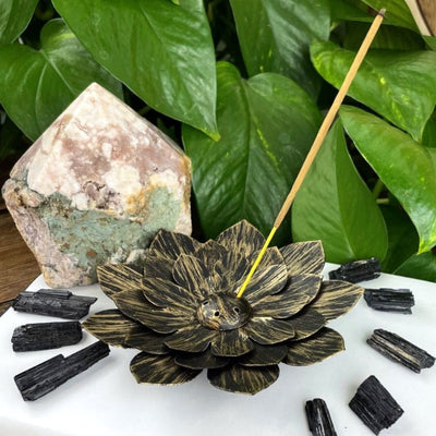 Metal Lotus Incense Holder Burner in golden color with stones around it