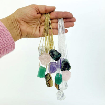 Hand holding up Healing Stone Necklaces on white background