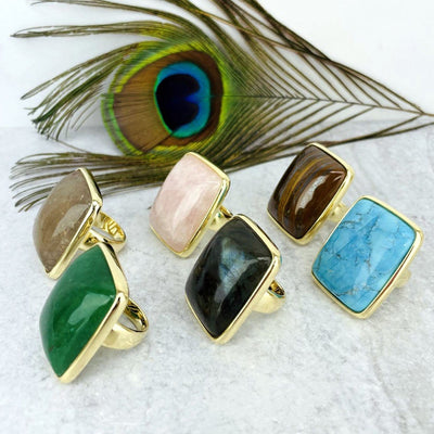 angled shot of gold stone rings with peacock feather in the background