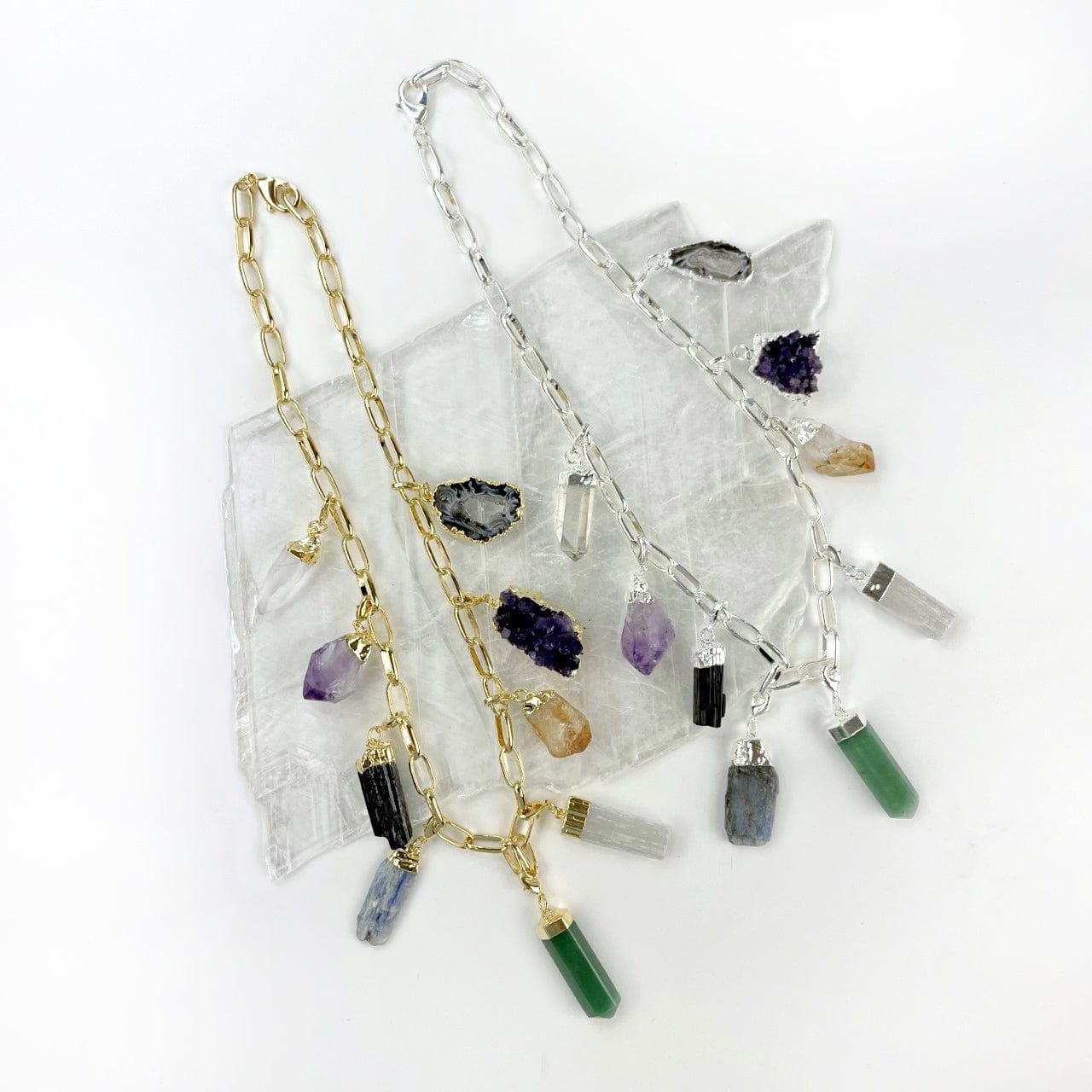 Gemstone and crystal charm necklace in gold and silver laying on a table