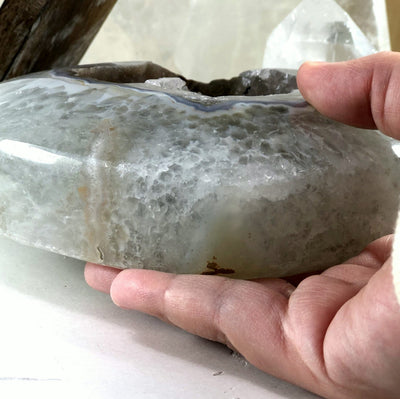 An angled view of Agate Druzy Heart - Natural (DOOAK-S24-25) in a hand showing agate thickness.