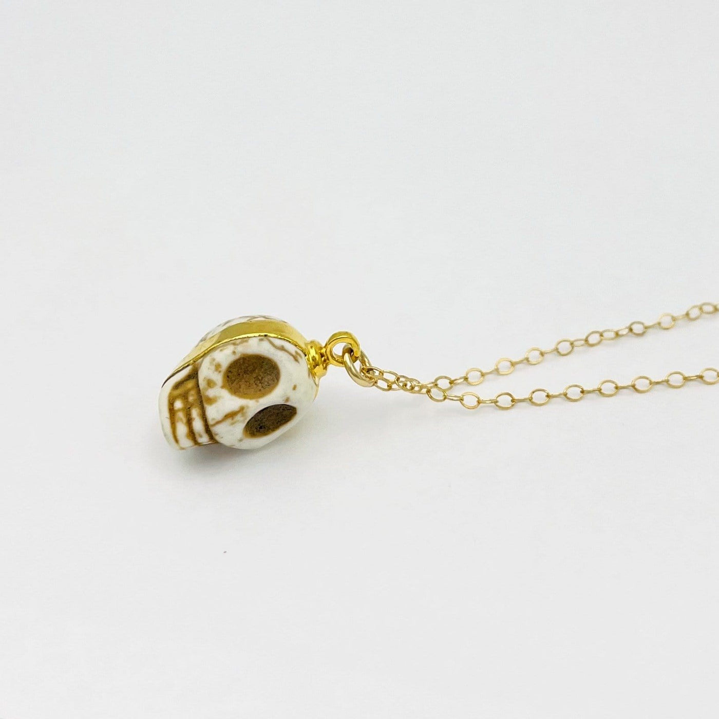 white howlite skull pendant necklace laying on its side on white background