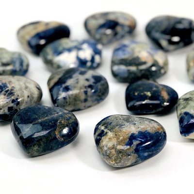 angled view of many sodalite heart shaped stones on white background for thickness