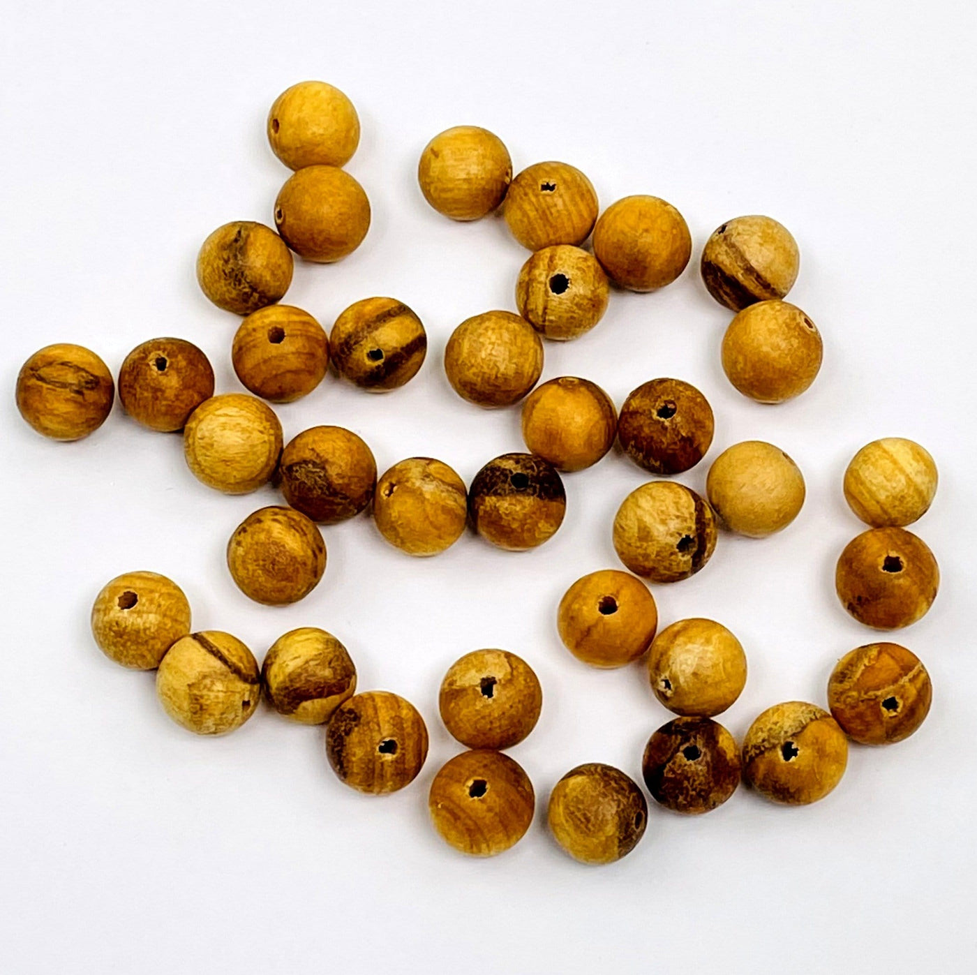 multiple drilled palo santo beads on a white background 