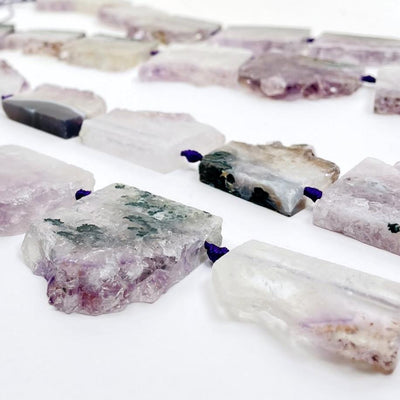 side view of amethyst slice beads on white background