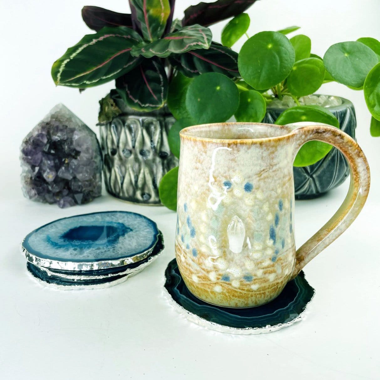 3 Teal Agate coasters with a silver electroplated edge stacked next to 1 piece that is under a coffee cup for display, Slices measure about 3.5-5"