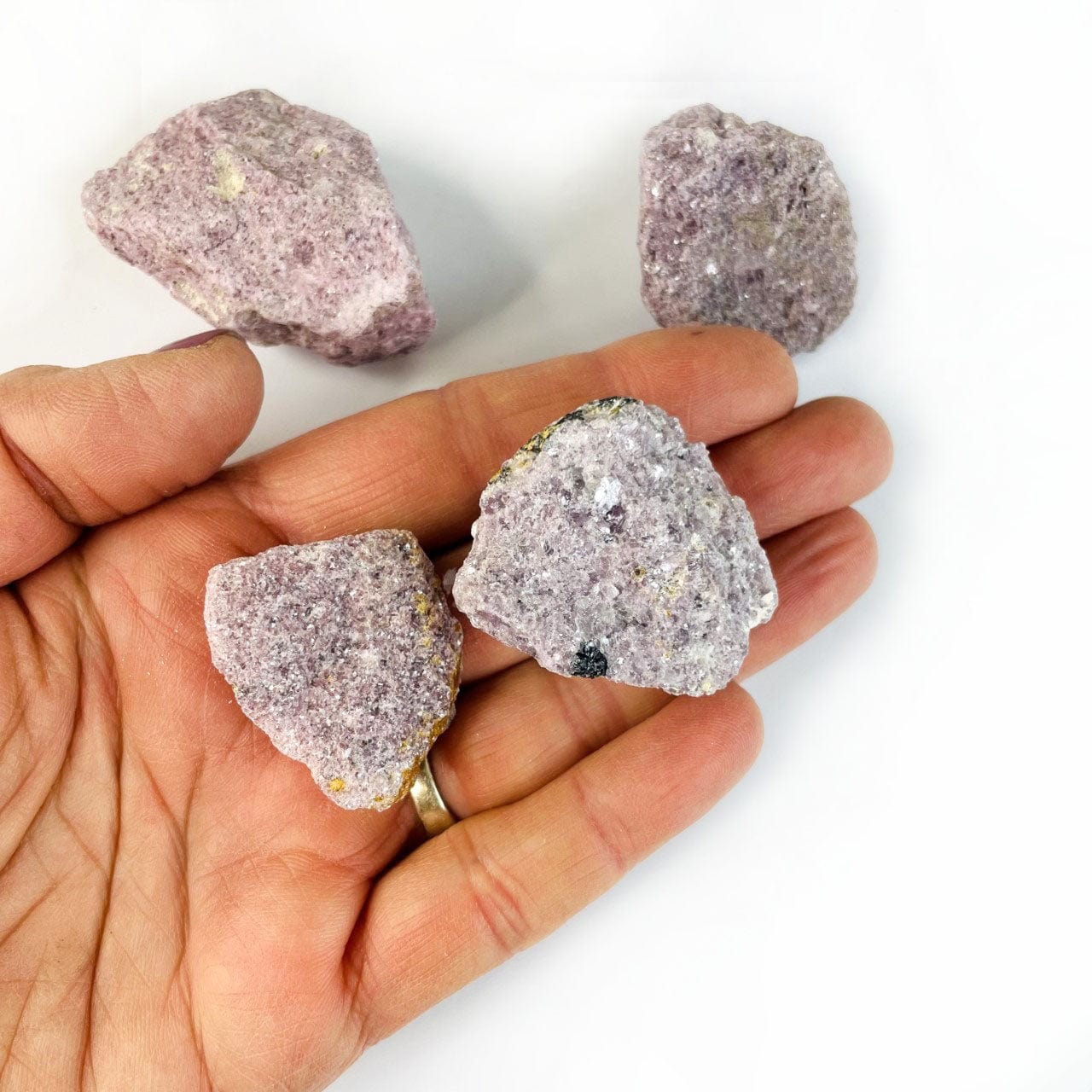 2 pieces of rough lepidolite in a hand for size reference