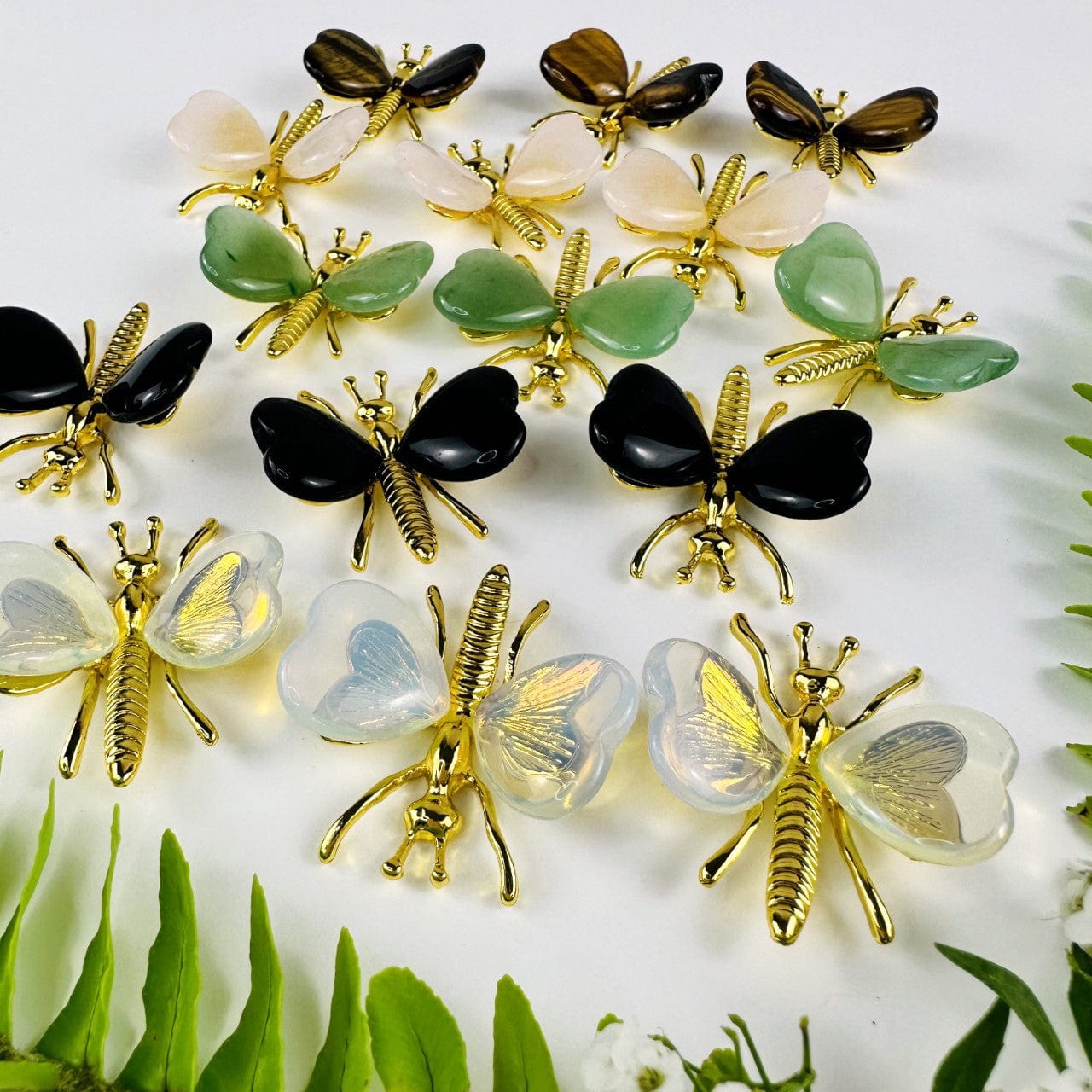 Gemstone Butterflies with Gold Tone Body on a table showing the assorted stones we carry from back and fronts