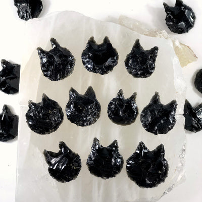 16 obsidian cats laying on top of a selenite platter