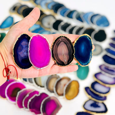 Picture of our purple, pink, black and blue agate slices plated edge top drilled, being displayed in hand for size reference.