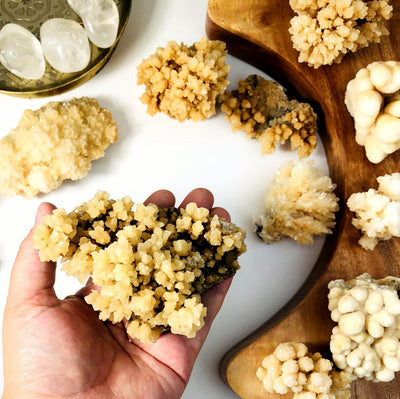 a larger Calcite Druzy Formations with more Calcite Druzy Formations in the background on a white and wood backdrop