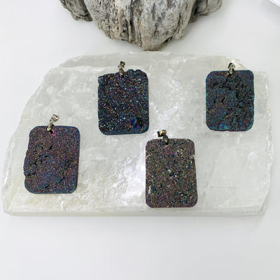Photo of all The rainbow titanium druzy pendants for his listing. The pendants are being displayed right next to each other on a selenite platform. However, the selenite platform wont be included with this items. 