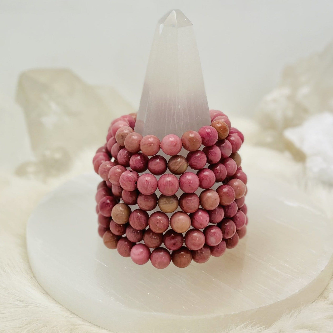 rhodonite bracelets stacked on a stand