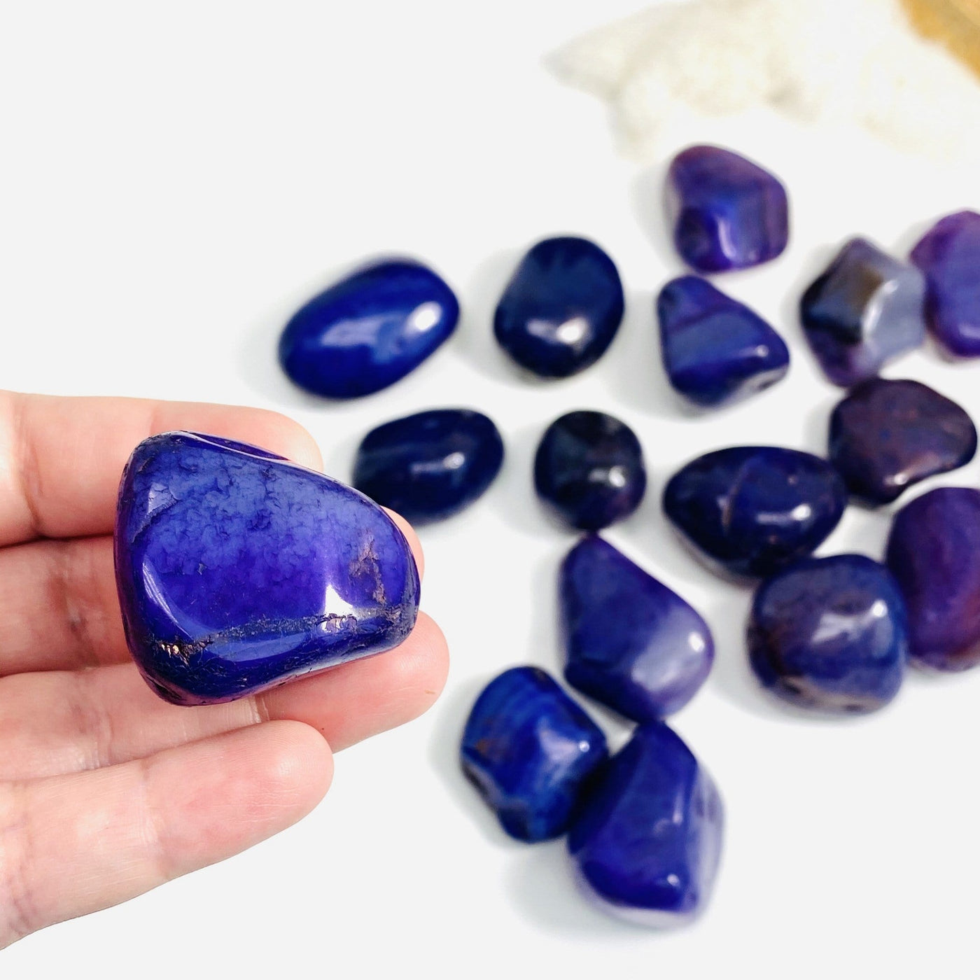 Single Purple Dyed Agate Tumbled Gemstones on hand for size comparison