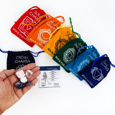The crown chakra set of 5 stones in a hand over the pouch and other sets behind