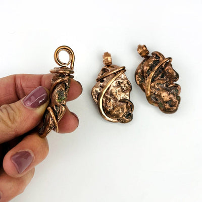 3 Copper Nugget freeform pendants with one in a hand for size reference and showing side thickness