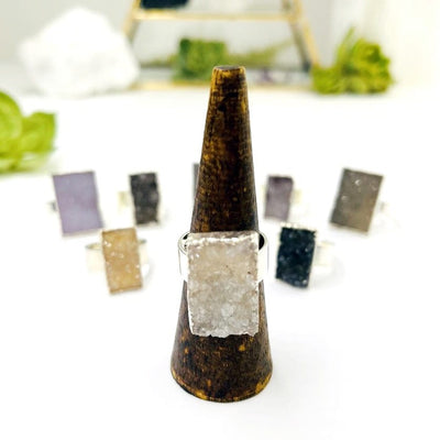Quartz Druzy Rectangle Adjustable Rings with one on a stand up close