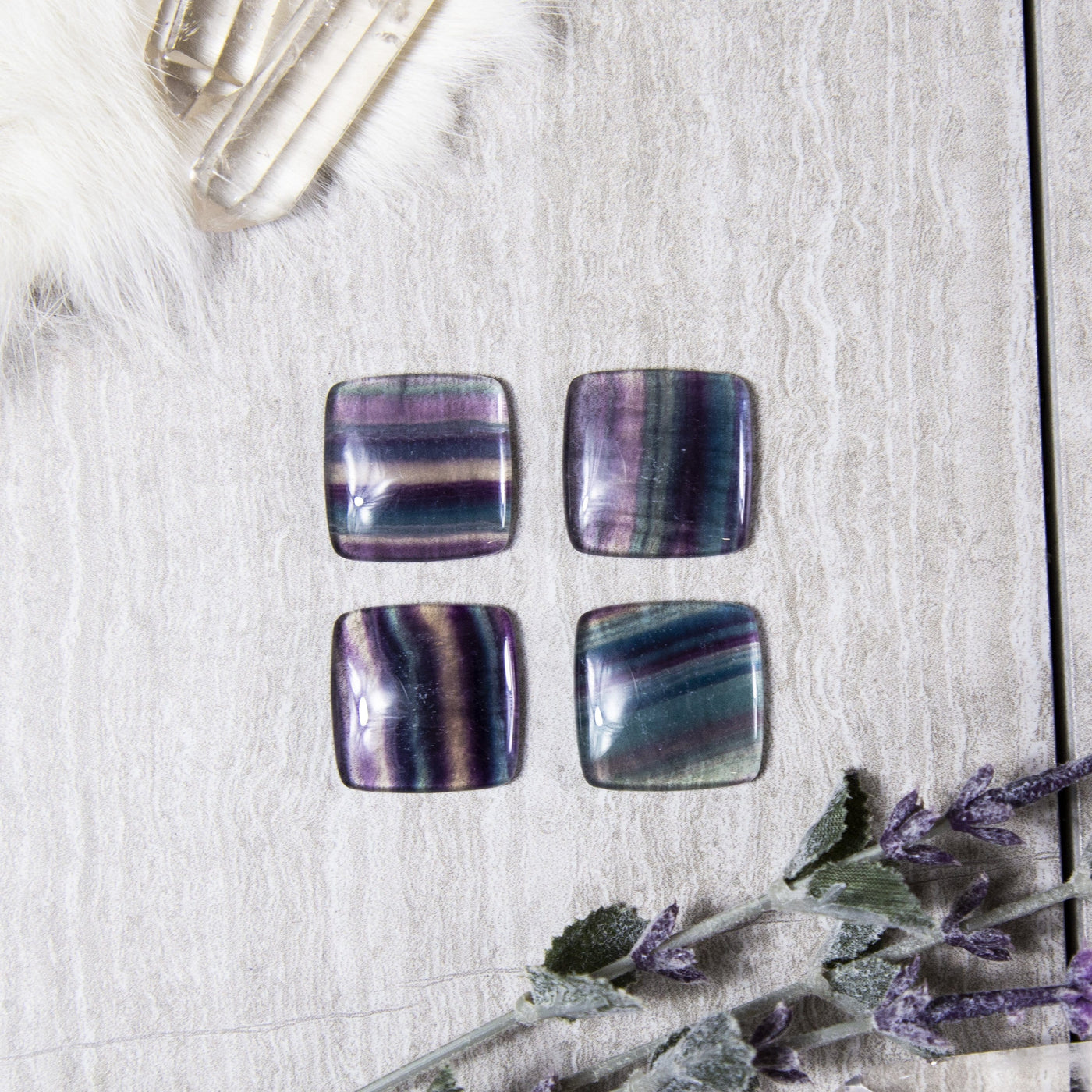 4 rainbow fluorite square cabochons on gray background with decorations