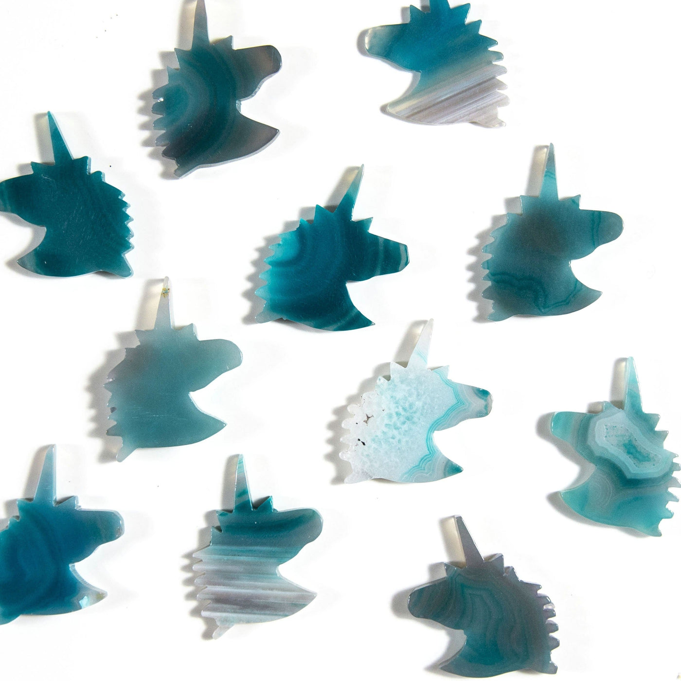 Teal agate unicorn heads being displayed on a white background. 