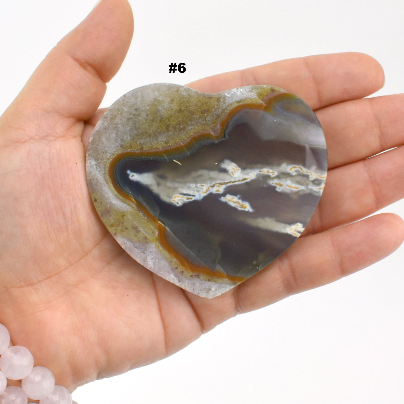 Agate heart slice #6 in a hand with a white background.