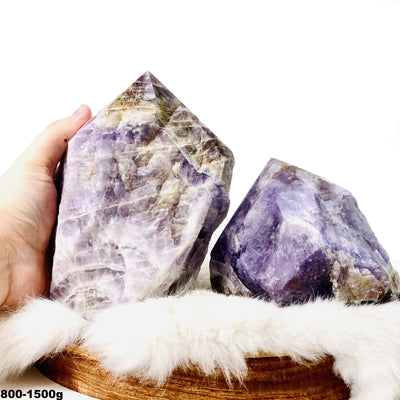 Picture of two amethyst ametrine semi polished points displayed on a fury surface.
