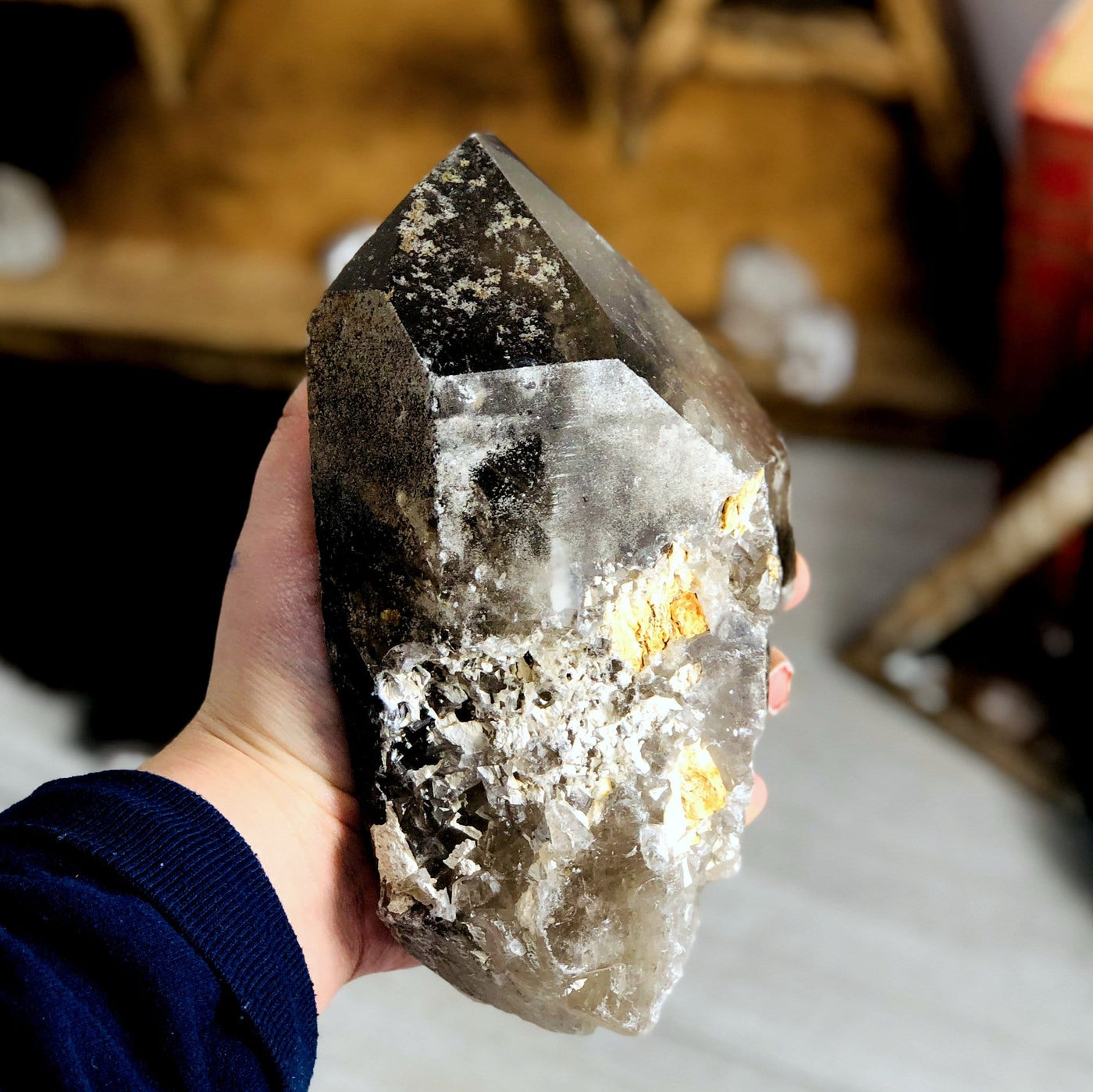 side view of smokey quartz semi-polished point in hand for thickness