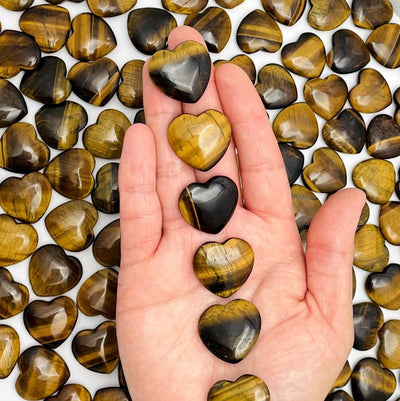 Hand holding 6 Tiger Eye Hearts and many are shown on the background
