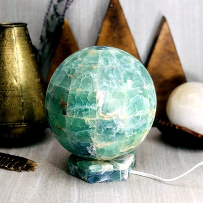 Rainbow Fluorite Sphere Lamp with various decorations in the background