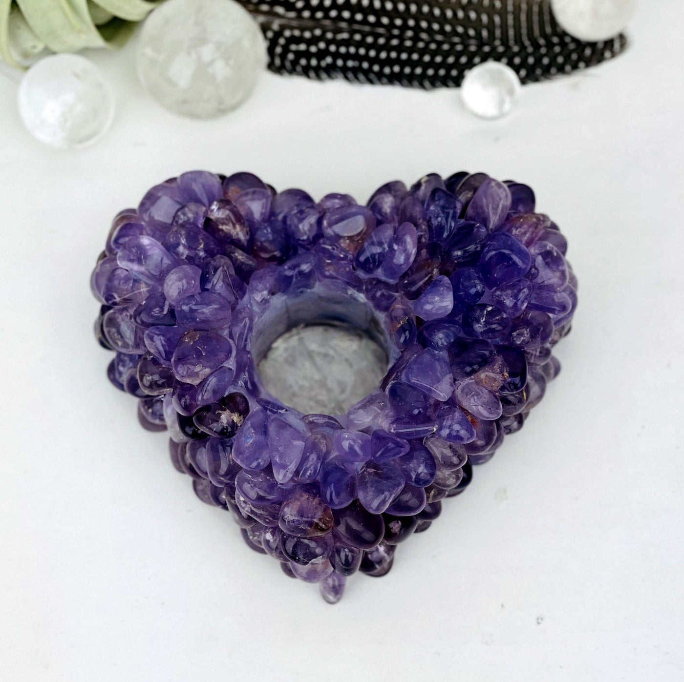 up close shot of amethyst tumbled stone heart candle holder with decorations in the background