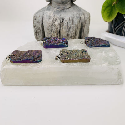 Side Photo of all The rainbow titanium druzy pendants for his listing. The pendants are being displayed right next to each other on a selenite platform. However, the selenite platform wont be included with this items.