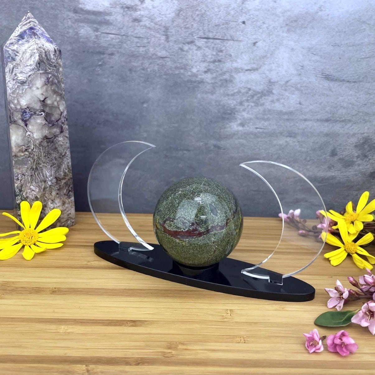 An angled Acrylic Sphere Holder Crescent Moons shown holding a sphere in an alter surrounded by flowers.