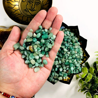 Green Quartz chips in a hand with more in a bowl in the background.