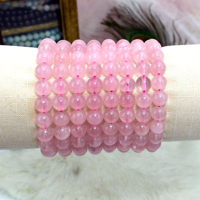 display holding 8 Rose Quartz Round Bead Bracelets with decorations blurred in the background
