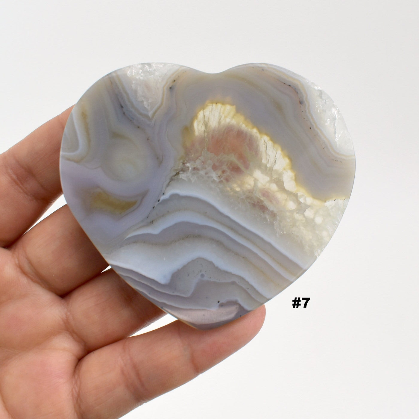 Agate heart slice #7 in a hand with a white background.
