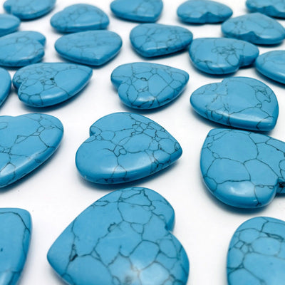 angled shot of turquoise howlite hearts on white background