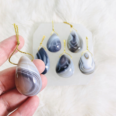 One of the agate pendants is being held for size reference.