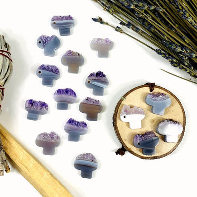 Amethyst slice cut into mushroom shapes with a drill hole on the side.  This photo shows an assortment as they range in colors and patterns with shades of white, gray, brown, purple and tan.