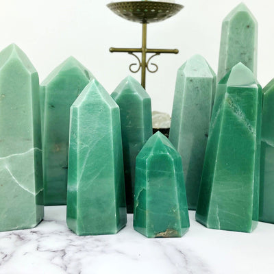 An assortment of green quartz towers on a white marble background.