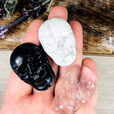 hand holding 3 different skull cabochons with decorations in the background