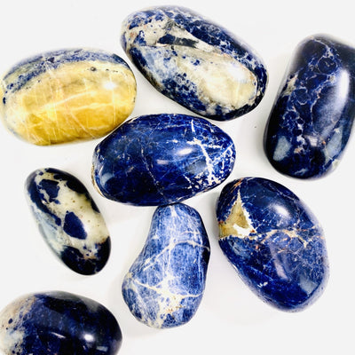 overhead view of many sodalite large tumbled stones on white background for possible variations