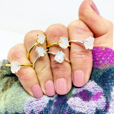 rough moonstone rings in gold over sterling and sterling on a woman's hand.  She is wearing 3 silver rings and 3 gold rings