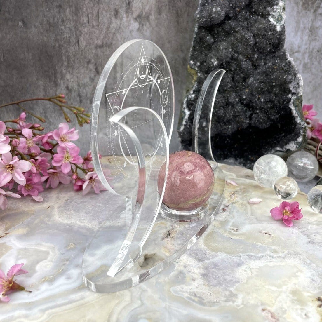 A side angle of an Acrylic Sphere Holder Crescent Moons - Six Pointed Star in an alter surrounded with flowers and crystals.