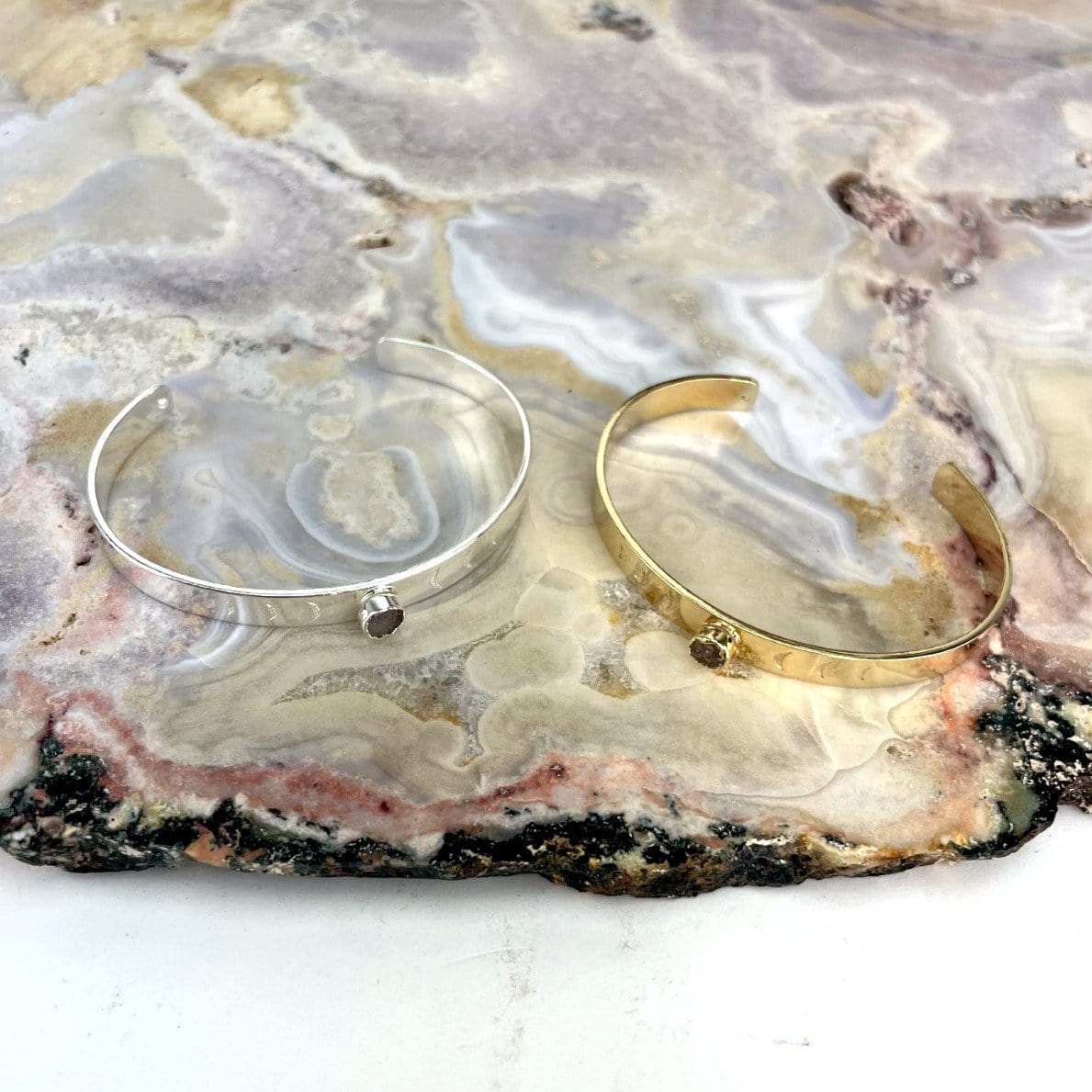 top view of one silver and one gold moon phase druzy bracelet on agate slab