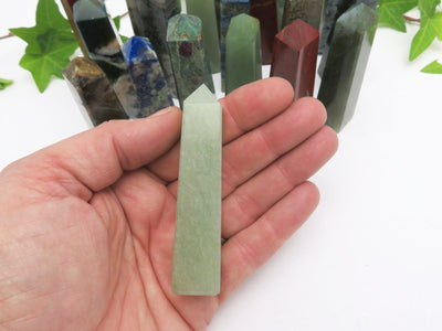 hand holding up aventurine obelisk for size reference with others in the background