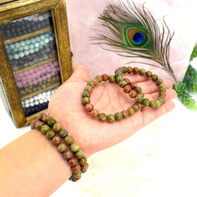 2 Unakite Round Bead Bracelets bracelets in hand for size and 2 Unakite Round Bead Bracelets on the wrist for size