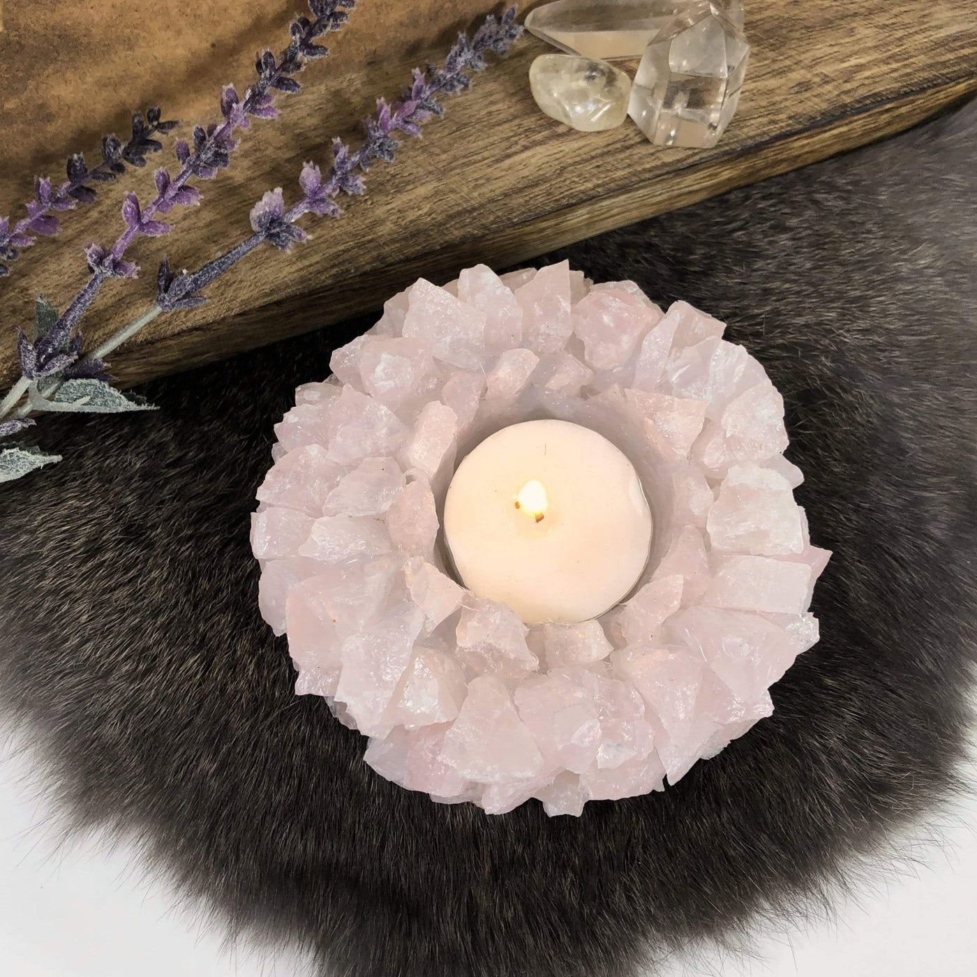Rose Quartz Candle Holder with candle inside on fur background with decorations 