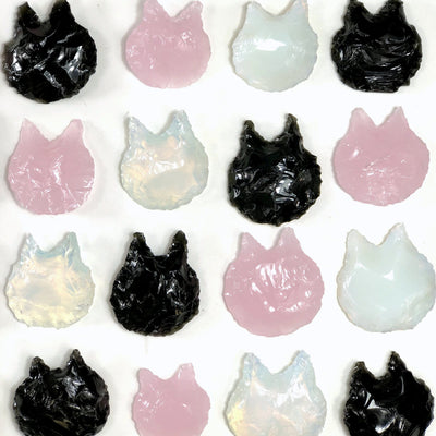 12 glass crystal cats laid out on a white background