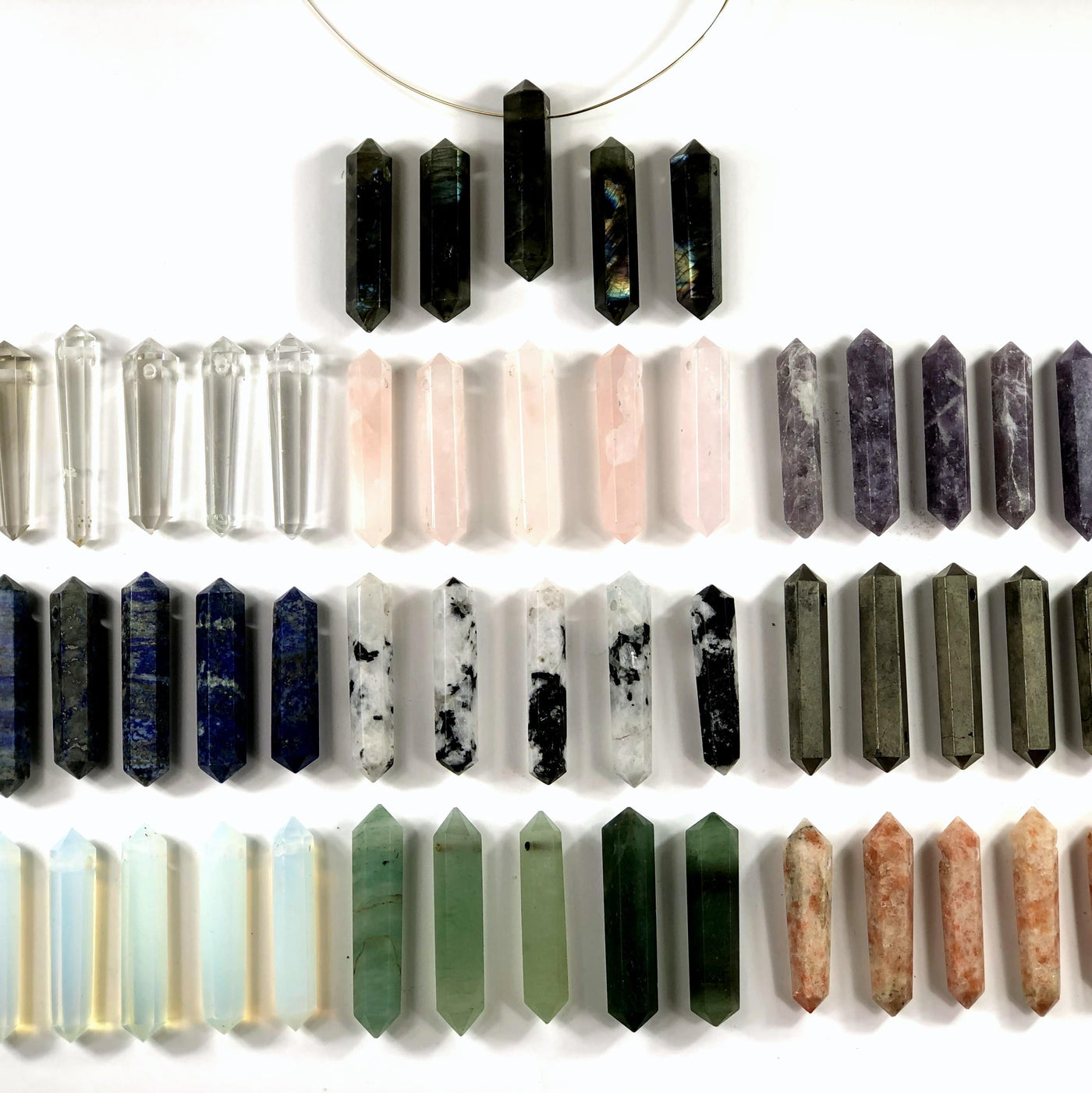 multiple top drilled double terminated gemstones displayed to show the differences in the crystal types