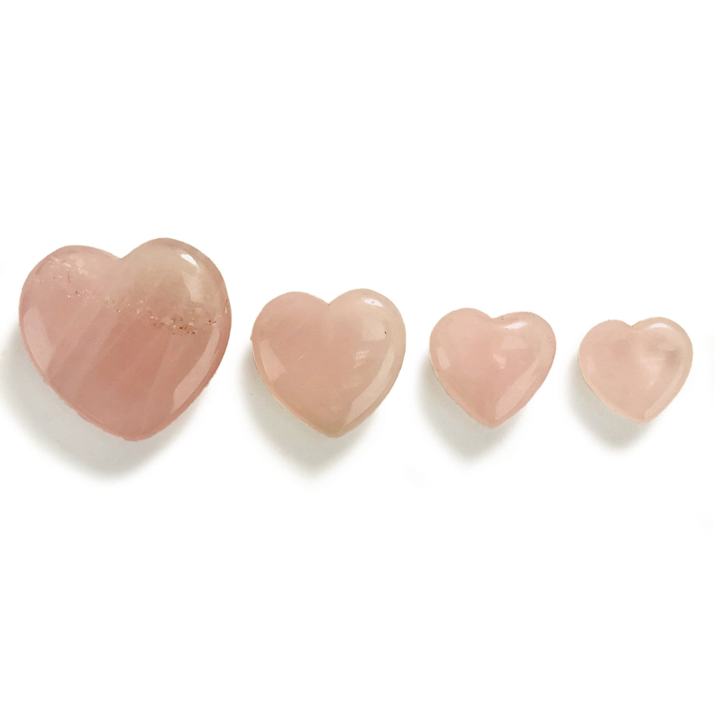 4 Rose Quartz Hearts of different sizes lined up on white background